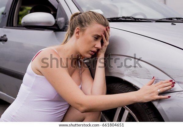 Frustrated young woman checking pointing at car\
scratches and dents outdoors during the day,  car crash accident, \
accident insurance. Stressed Driver Sitting At Roadside.Young woman\
is terrified 