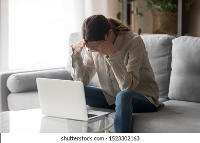 Frustrated young woman student sit on sofa at home feeling headache depressed after reading bad online news email on laptop, upset stressed having problem, panic about failed exam test result concept - Shutterstock ID 1523302163