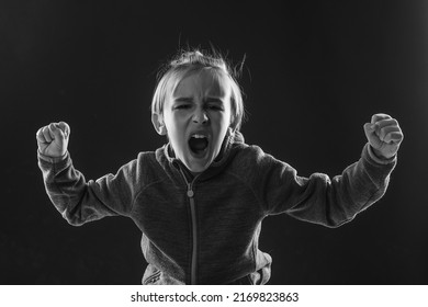 Frustration concept. Angry boy shouting in dark. Kid mad shouting and yelling with aggressive expression and arms raised. - Shutterstock ID 2169823863