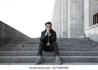 frustration of a middle-aged european man sitting on the steps of a building - Powered by Shutterstock