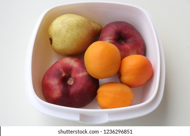 Frutta, Spain - August 25, 2017: A Tupperware Bowl With Some Fresh Fruit: Three Orange Apricot, Two  Red Peaches And One Green Pear