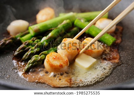 Fry asparagus and scallops in butter in a frying pan