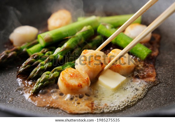 Fry\
asparagus and scallops in butter in a frying\
pan