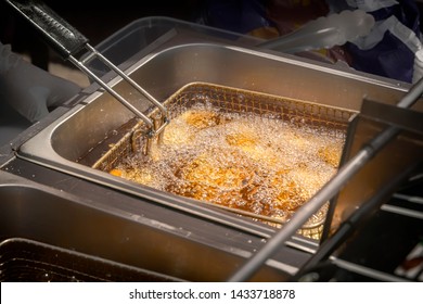 Fryer from the food net is lowered into boiling oil in an outdoor fast-food restaurant. Close-up