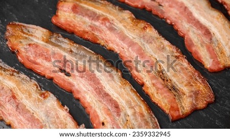 Frying bacon slices in oven. Crispy pieces of fried delicious bacon. Traditional breakfast