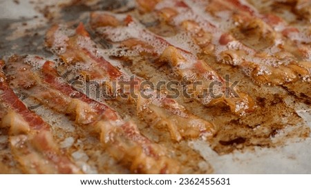 Frying bacon slices in oven. Crispy pieces of fried delicious bacon. Traditional breakfast
