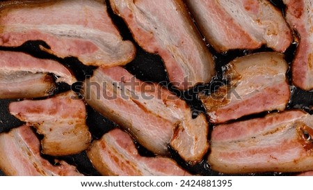 Frying bacon top view. Delicious crispy bacon strips cooking on a flat top grill