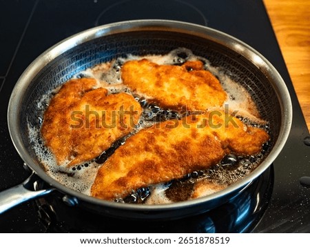 Frying crispy breaded chicken cutlets in frying pan, close-up