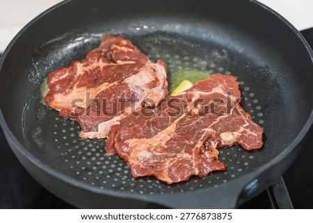 frying fresh raw beef steak in a flat bottom pan