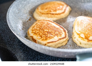 Frying kefir based pancakes in cooking pan on an electric stove.
