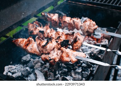 Frying meat pork on the grill. Shish kebab for summer party. Shashlik on wooden panels and open fire.