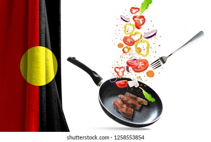 Frying Pan With Falling Vegetables And Meat, Isolated. On The Background Of The Flag Of Australian Aboriginal