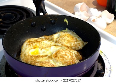 Frying Pan Filled With Cooked Eggs Atop A Stovetop Electric Burner With Broken Eggshells On The Adjacent Surface.