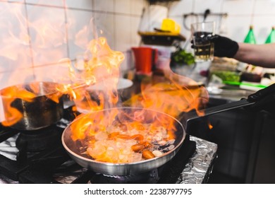 Frying pan in flames. Professional chef cooking ingredients for shrimp pasta with the use of fire. Restaurant kitchen. High quality photo