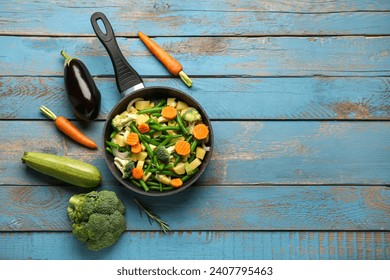 Frying pan with fresh vegetables on blue wooden background - Powered by Shutterstock