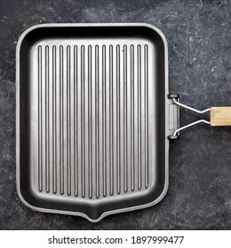 Frying Pan Grill On Black Grunge Background, Top View. Empty Cast Iron Griddle, Overhead View. Square Grill Pan On Black Shabby Table.