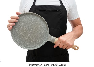 Frying Pan In The Hands Of A Man In A Black Apron Isolated On A White Background. Cooking Concept