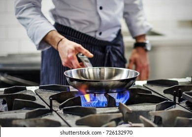 Frying pan on a gas stove. Chef controls the cooking process