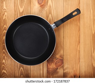 Frying Pan On Wooden Table Background. View From Above