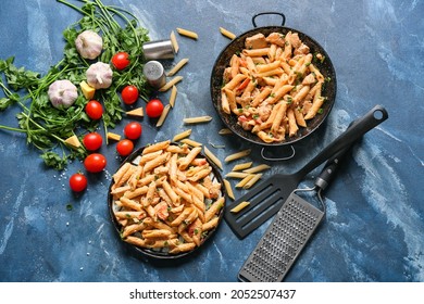 Frying Pan And Plate With Tasty Cajun Chicken Pasta On Color Background