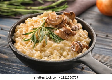 Frying pan with risotto and mushrooms on wooden table