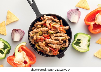 Frying Pan With Tasty Beef Fajita, Vegetables And Nachos On White Background