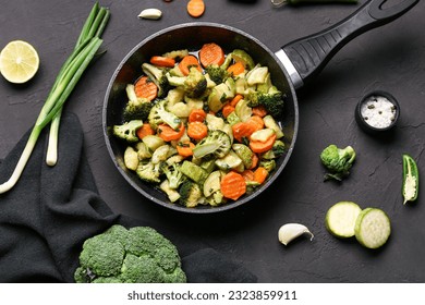 Frying pan with tasty vegetables on black background - Powered by Shutterstock