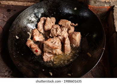 Frying Round Fried Cubes With Beef Bottom In A Cast-iron Skillet, Grilling Meat In Olia On The Fire
