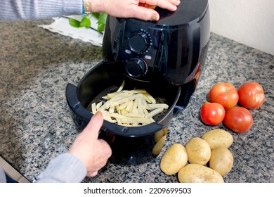 Frying sliced potatoes in the airfryer, with potatoes and tomatoes next - Shutterstock ID 2209699503
