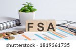 FSA word on wood blocks concept with chart, coins, notebook and glasses.Business concept