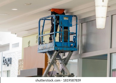 Ft. Lauderdale, FL / USA - 9/8/20202: Construction Worker On A Scissor Lift Working In A Mall Ceiling On The A/c, Can Lights, Insulation And Electrical Wiring To The Compressor At Attic Crawl Access. 