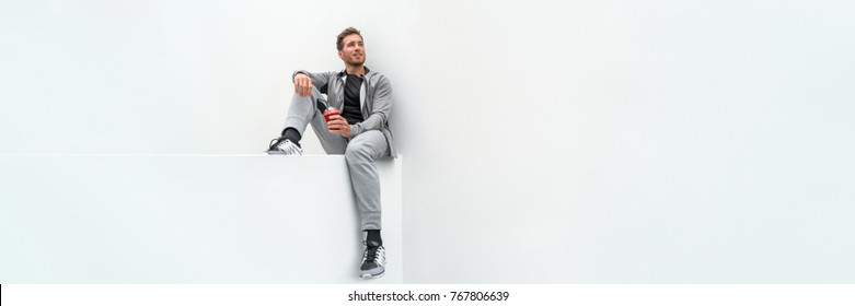 Ftiness Sport Man Drinking Smoothie Workout Banner Relaxing At Home In Gym Jogging Pants Activewear Outdoor. Athlete Sitting On White Background.