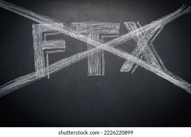 FTX is written in white chalk on a black board and crossed out. Close-up. Concept of bankruptcy and collapse of FTX cryptocurrency exchange. Free space to insert text