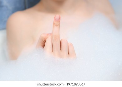 Fuck You Sign By Woman Hand In Foam In Bath, Middle Finger Sign, Closeup View. A Sign Of Aggression, Indifference And Rejection, Rudeness And Boorishness.