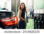 Fuel for the automobile. A young woman at a gas station with her car.