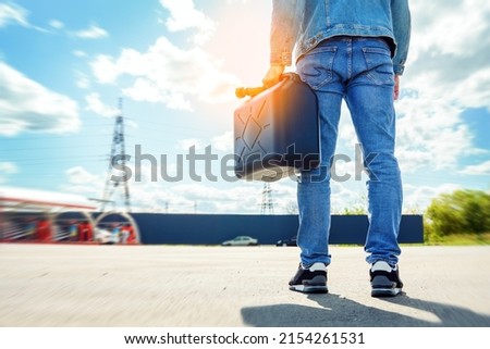 Fuel canister in the hands of a man standing with his back to us. Fuel reserve in jerrycan. Lack of petrol or diesel at gas stations concept.