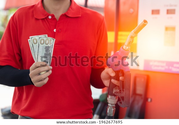 Fuel cost saving concept, staff worker hand\
holding money cash back at Gas\
station