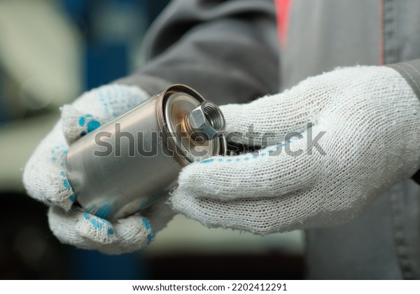 The fuel filter is new for the car\
engine. Close-up. An auto mechanic inspects the fuel filter,\
monitors the compliance and integrity of the spare\
part.