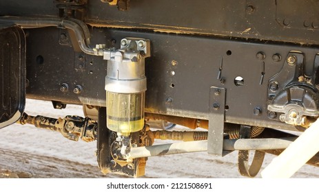 A Fuel Filter In A Truck. A Dirty Clear Fuel Filter With Black Rubber Hose Mounted On A Vehicle Chassis With Copy Space With Copy Space. Selective Focus