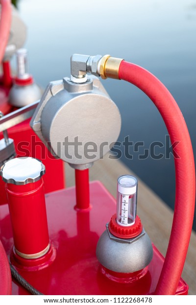 Fuel level\
gauge beside a pump cylinder and hose, on a portable marine\
gasoline tank, with space for text on\
top