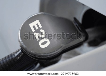 fuel nozzle with e20 label inserted into a car gas tank, close up of fueling a vehicle at a gas station, eco friendly ethanol gasoline blend, concept of ecology, automotive, transport. 