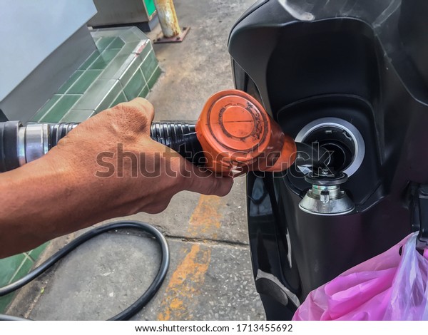The fuel\
nozzle is refilling the black\
motorcycle.