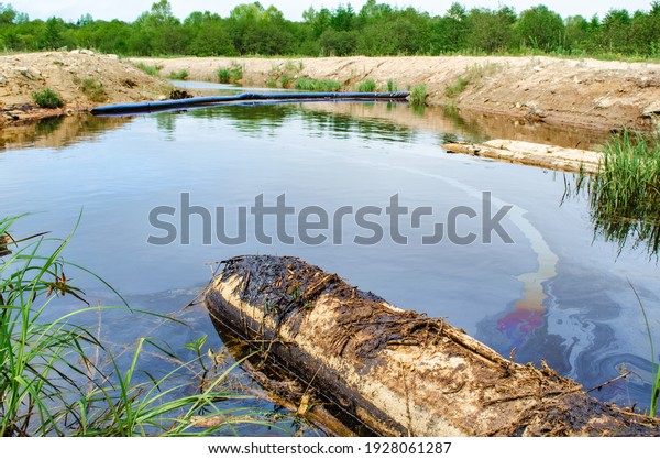 Fuel oil and waste oil fall into the pond. Oily\
mud floats near the shore of the pond-lake. Water pollution,\
environmental problems.