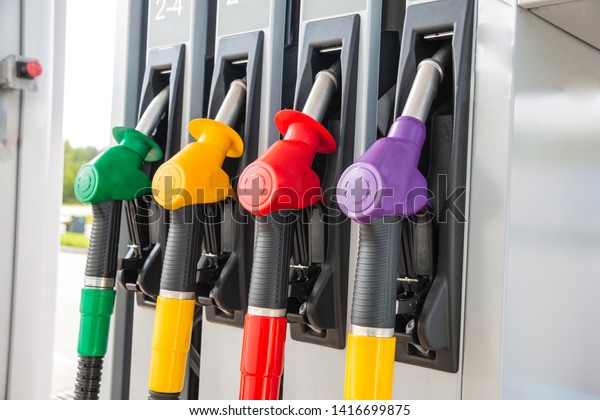 Fuel pistols at a gas station in\
different colors for different grades of gasoline close\
up