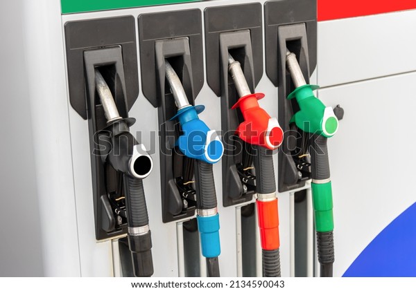 Fuel pump fill nozzles colored\
black, blue, red and green, background energy crisis\
concept