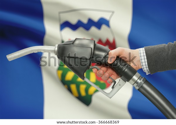 Fuel pump nozzle in\
hand with Canadian territories and provinces flags on background -\
Northwest Territories