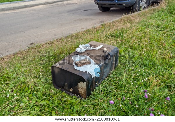 The fuel tank of the car is lying on the lawn in
the grass