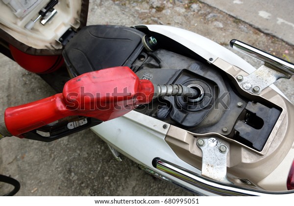 Fuel tank of\
motorcycle that opened for fuel ,oil or gasoline nozzle in pouring\
to motorcycle and high angle\
view.