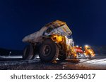 Fuel tanker car refueling large quarry dump truck in mining quarry, night work.