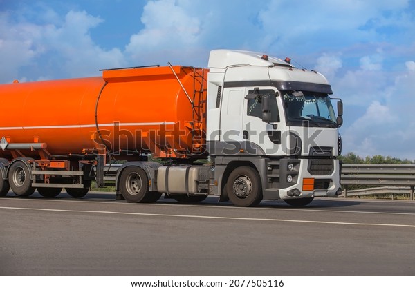 Fuel tanker truck moves on a country road against the\
background of the sky